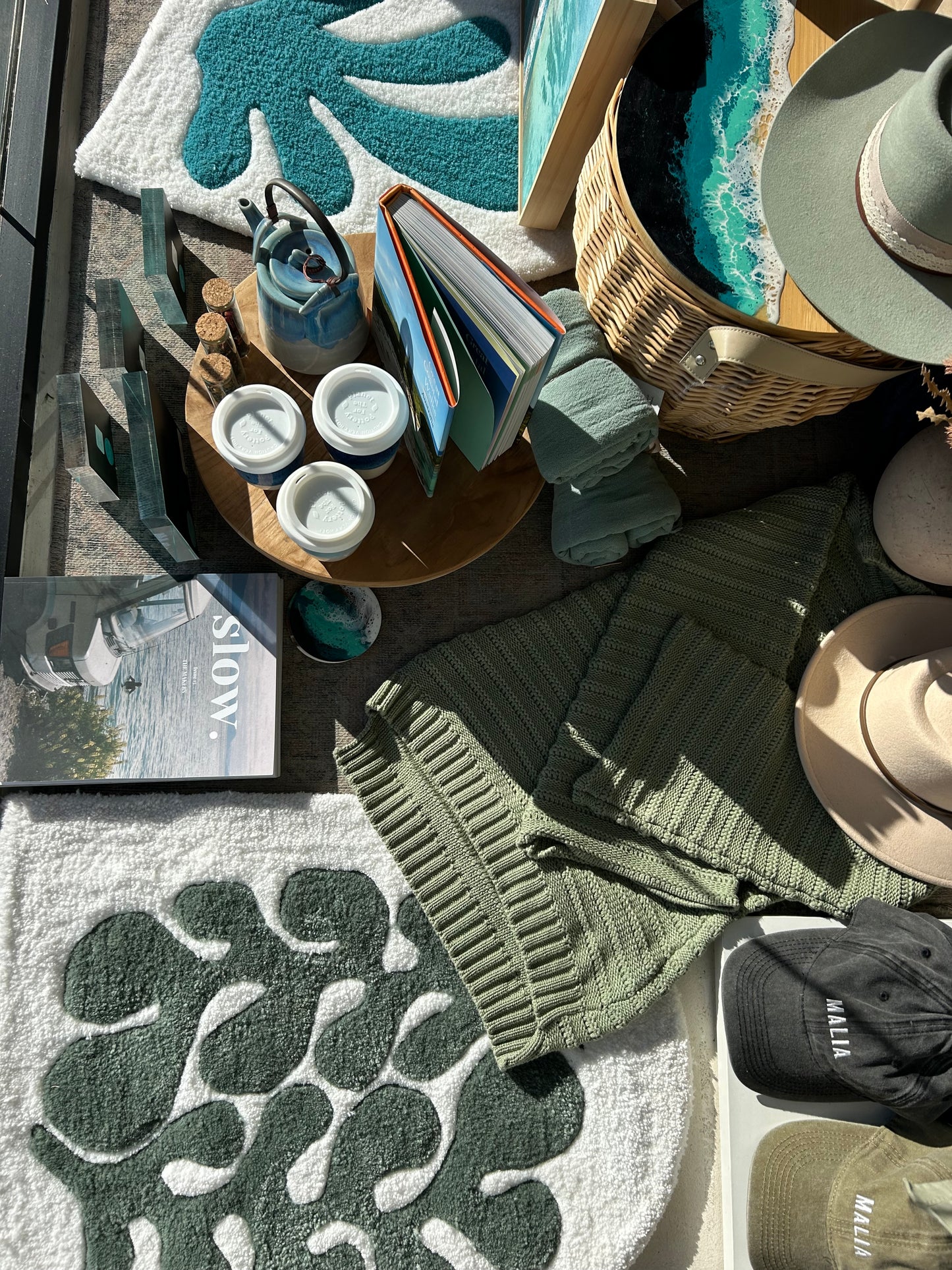 Tabletop setting with decorative items including a hat, books, and a basket on a textured surface.