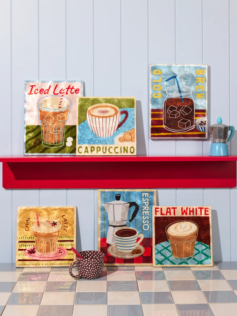 Decorative coffee-themed wall art on a red shelf against a light blue wall.