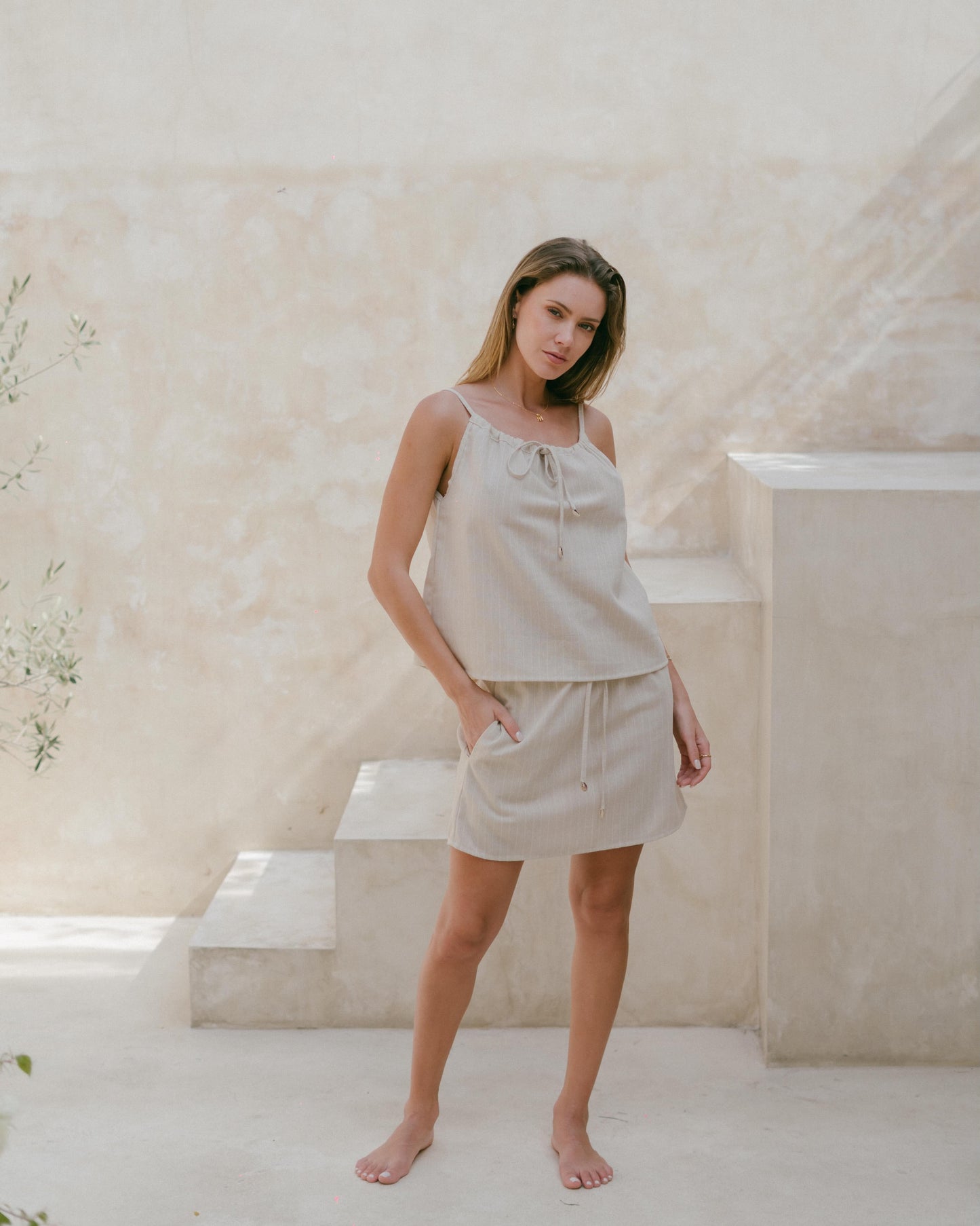 Lightweight neutral pinstripe top with adjustable straps and coastal-inspired shell accents.