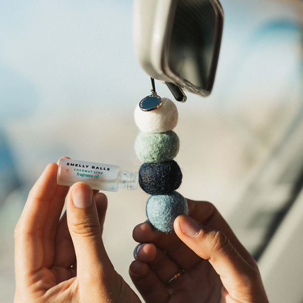 Car freshener with colorful beads held by a hand, with a blurred outdoor background