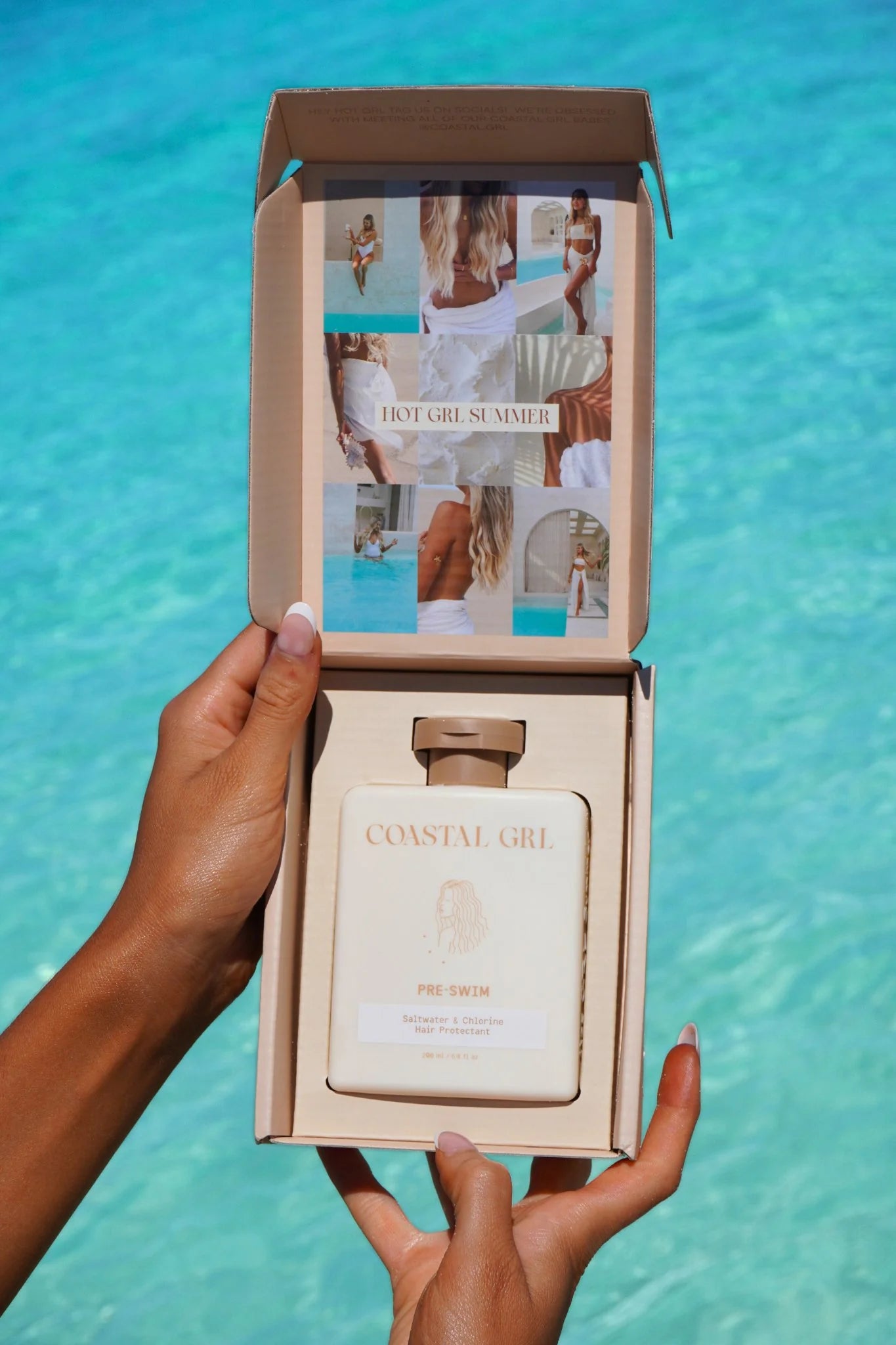 Person holding a 'Coastal Girl' product with a box against a blue water background